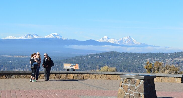 Family taking in the snow-capped Cascade panorama from the Pilot Butte summit viewpoint